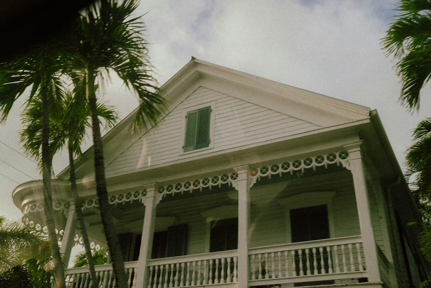 White wooden house with a decorated porch and palm trees
