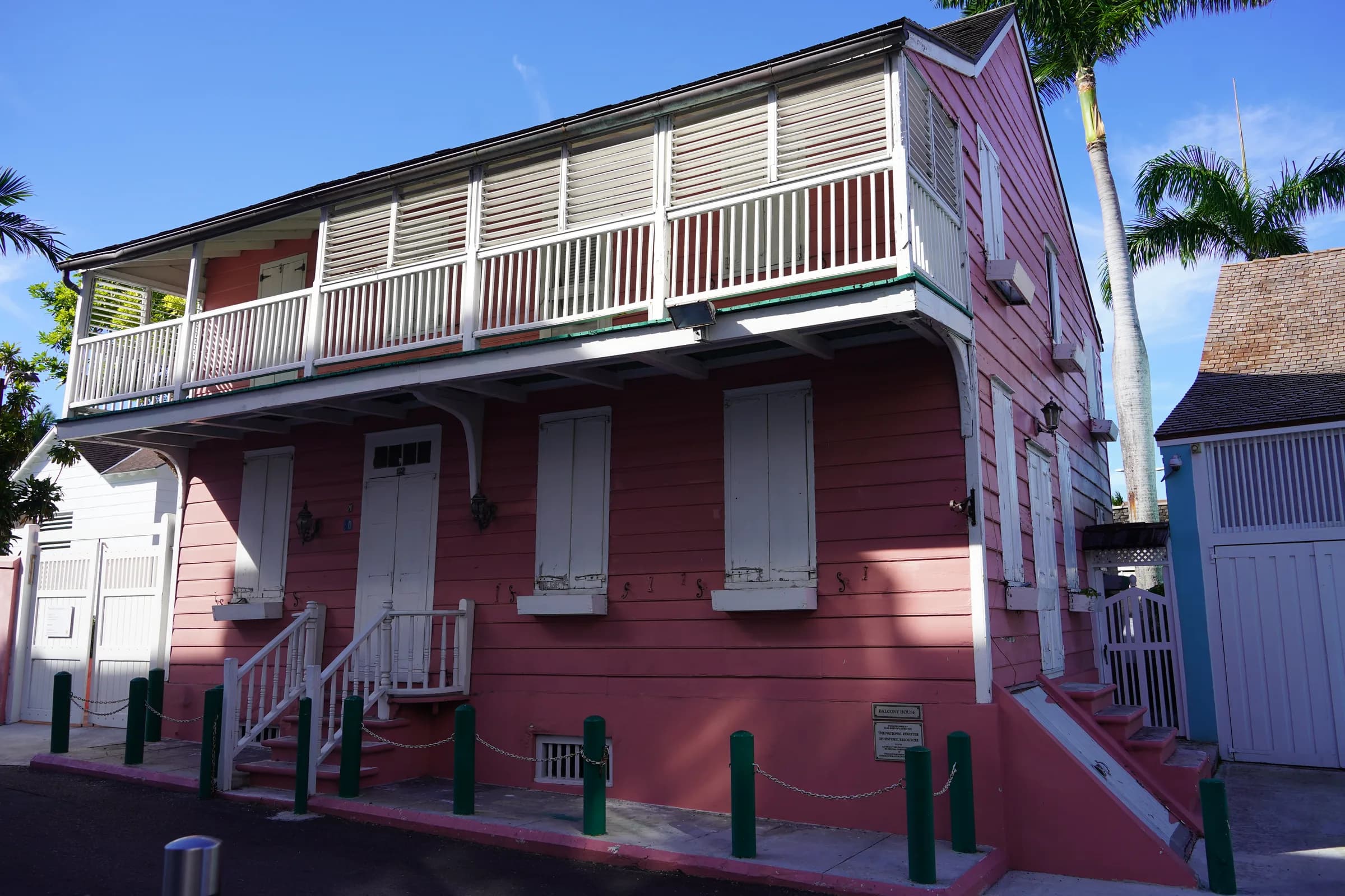 Pink clapboard house with a wooden balcony and shutters in downtown Nassau